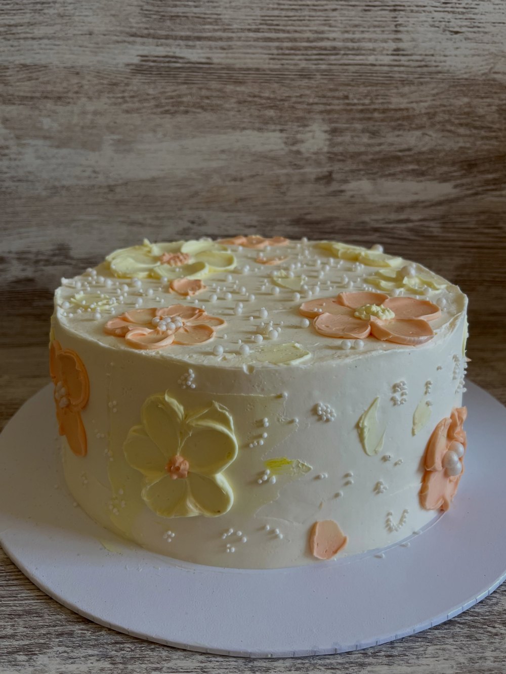 Pastís de buttercream amb flors en tons préssec i groc